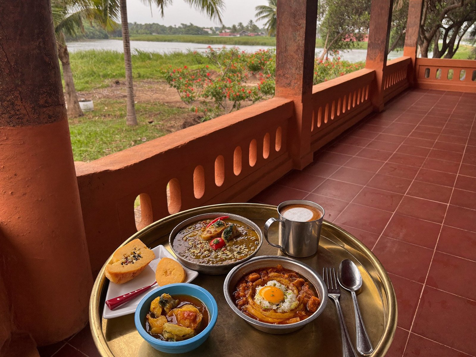 A Kerala meal laid out on a tray on the veranda overlooking the water
