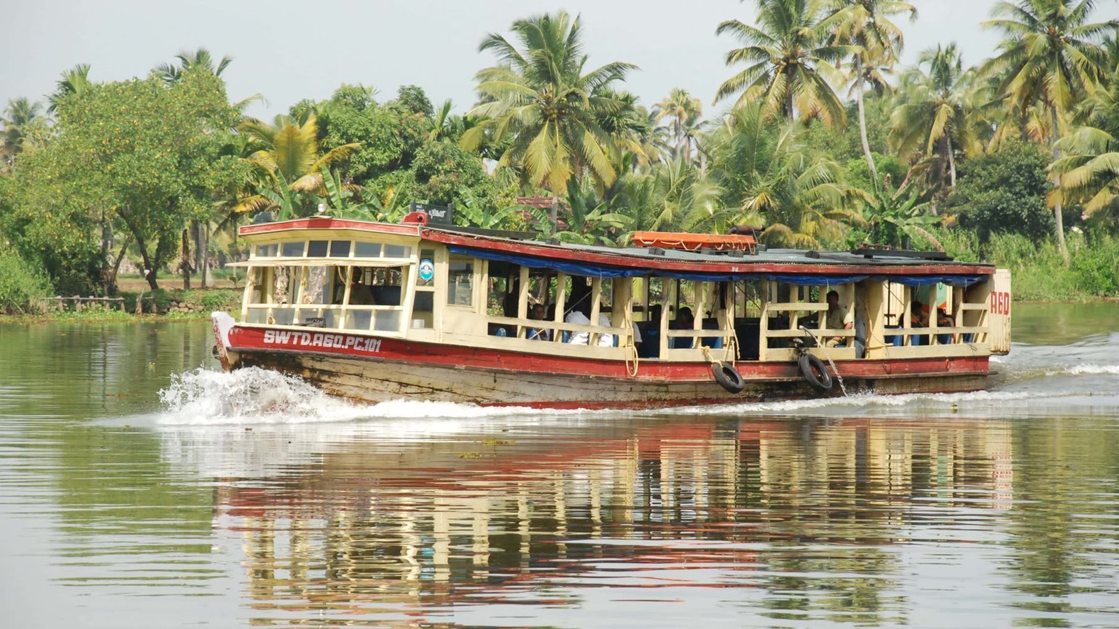 A Kerala houseboat passing along the backwater in front of the palms