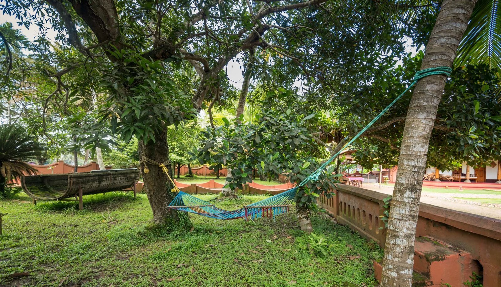 A hammock slung between trees in the garden with the water behind