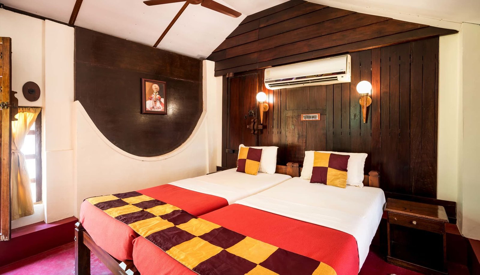 A guest room lined floor to ceiling in carved teak, with a bed on a red-oxide floor