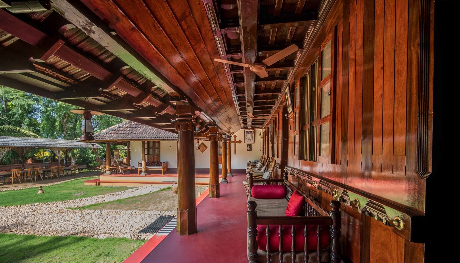 The long teak veranda of the house, red-oxide floor, carved pillars and low seating